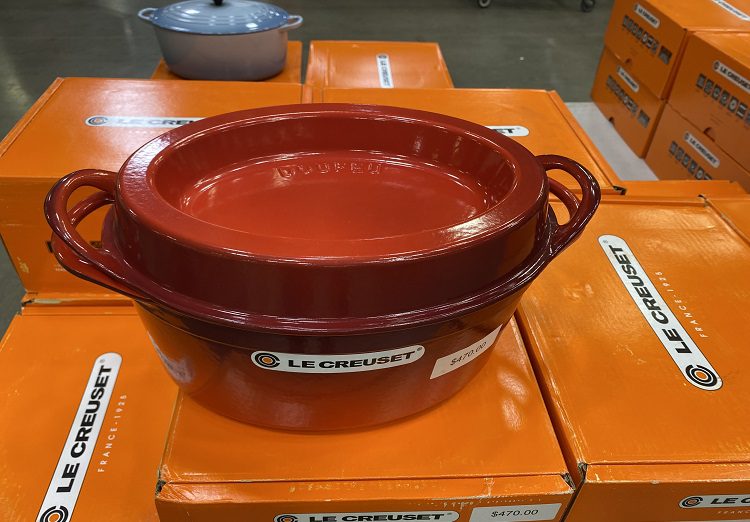 Closeup of Flame colored Le Creuset Doufou pot sitting atop more boxes of Le Creuset pots.